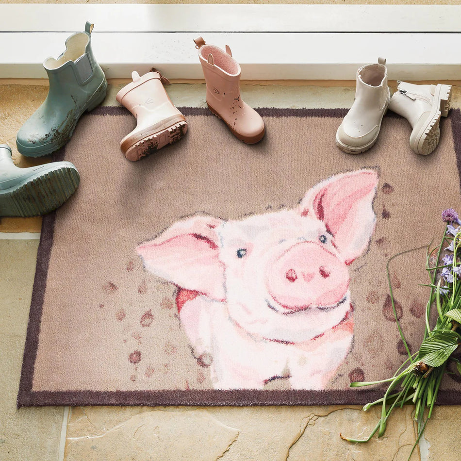 Doormat with a pig design on a floor with boots around it