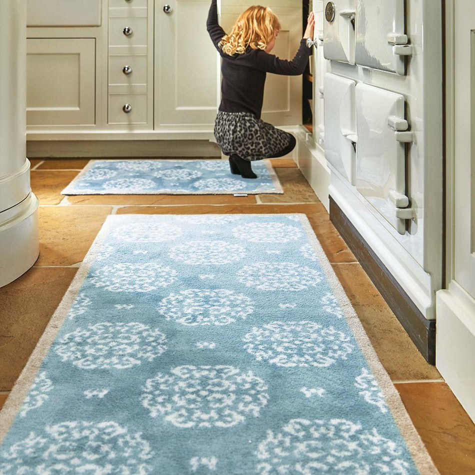 Woman stepping onto a blue patterned rug in a kitchen