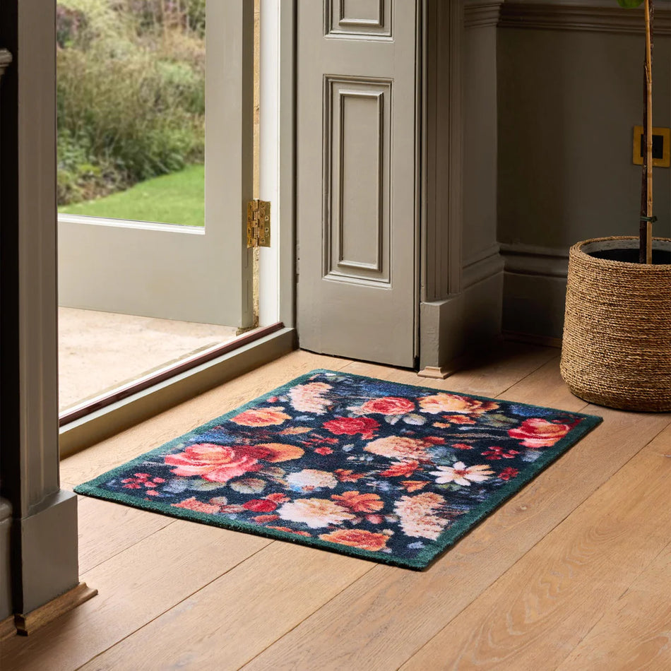 Floral patterned rug on a wooden floor in front of an open door.