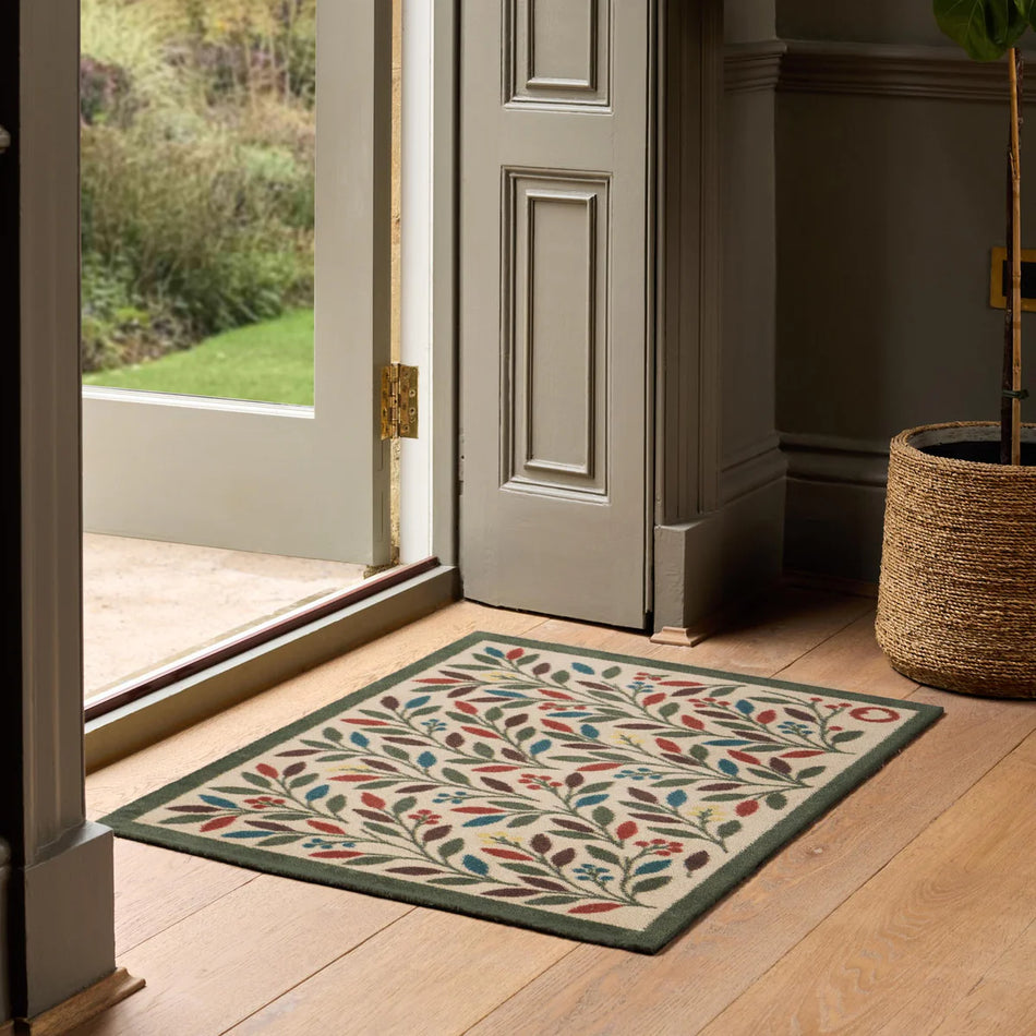 Decorative rug with floral pattern on wooden floor in front of a door