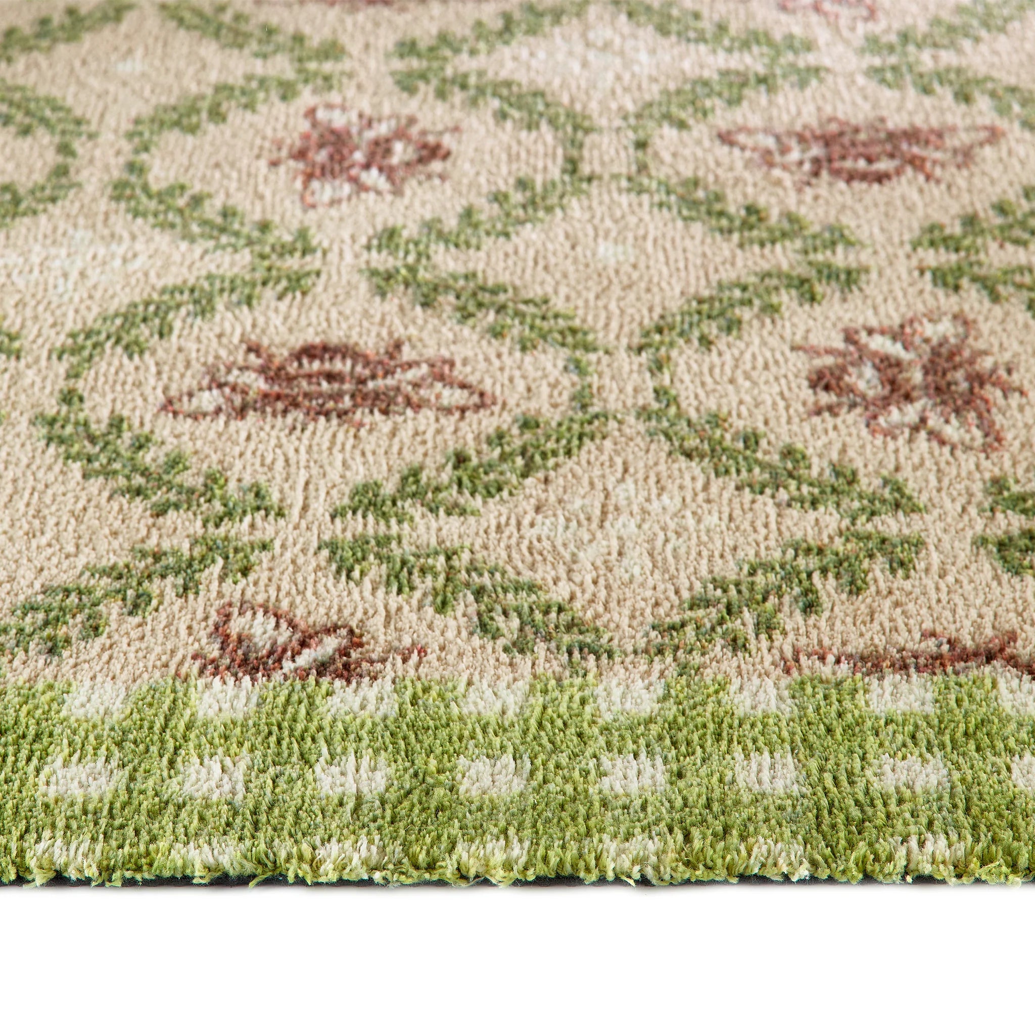 Close-up of a patterned rug with green and brown colors on a beige background