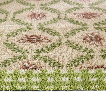 Close-up of a patterned rug with green and brown colors on a beige background