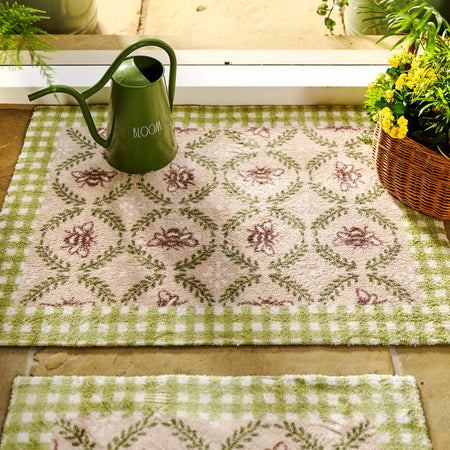 Decorative green and white checkered rug with floral patterns, accompanied by a green watering can and potted plants.