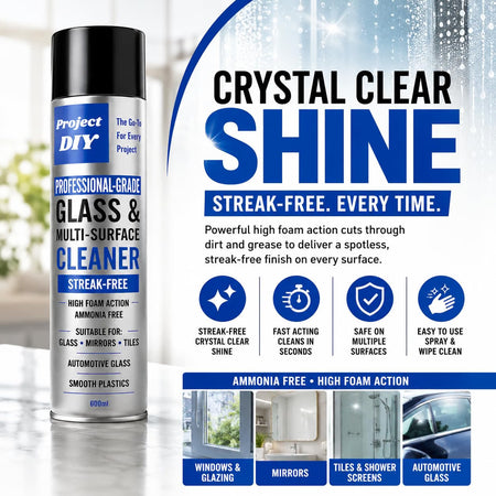 A bottle of Project DIY Crystal Clear Shine glass and multi-surface cleaner stands on a reflective surface against a bright, blurred interior background. The right side features large promotional text, feature icons, and usage examples for windows, mirrors, tiles, and automotive glass.