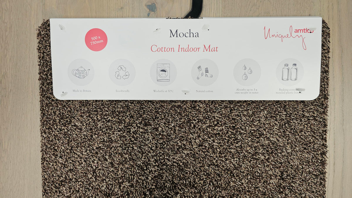 Brown doormat with a label indicating 'Mocha Cotton Indoor Mat' on a wooden floor.