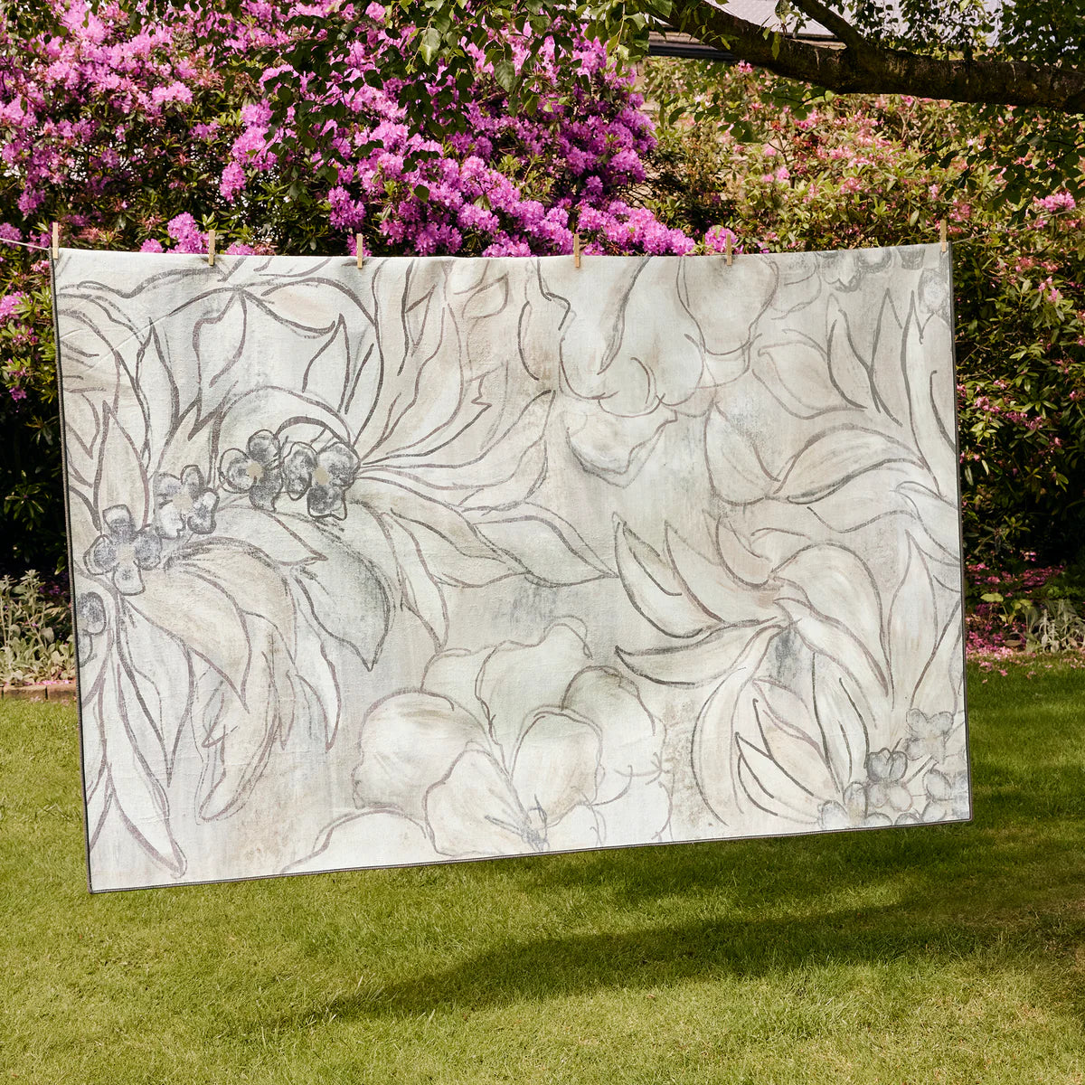 Decorative glass panel with floral design on a grassy area with pink flowers in the background