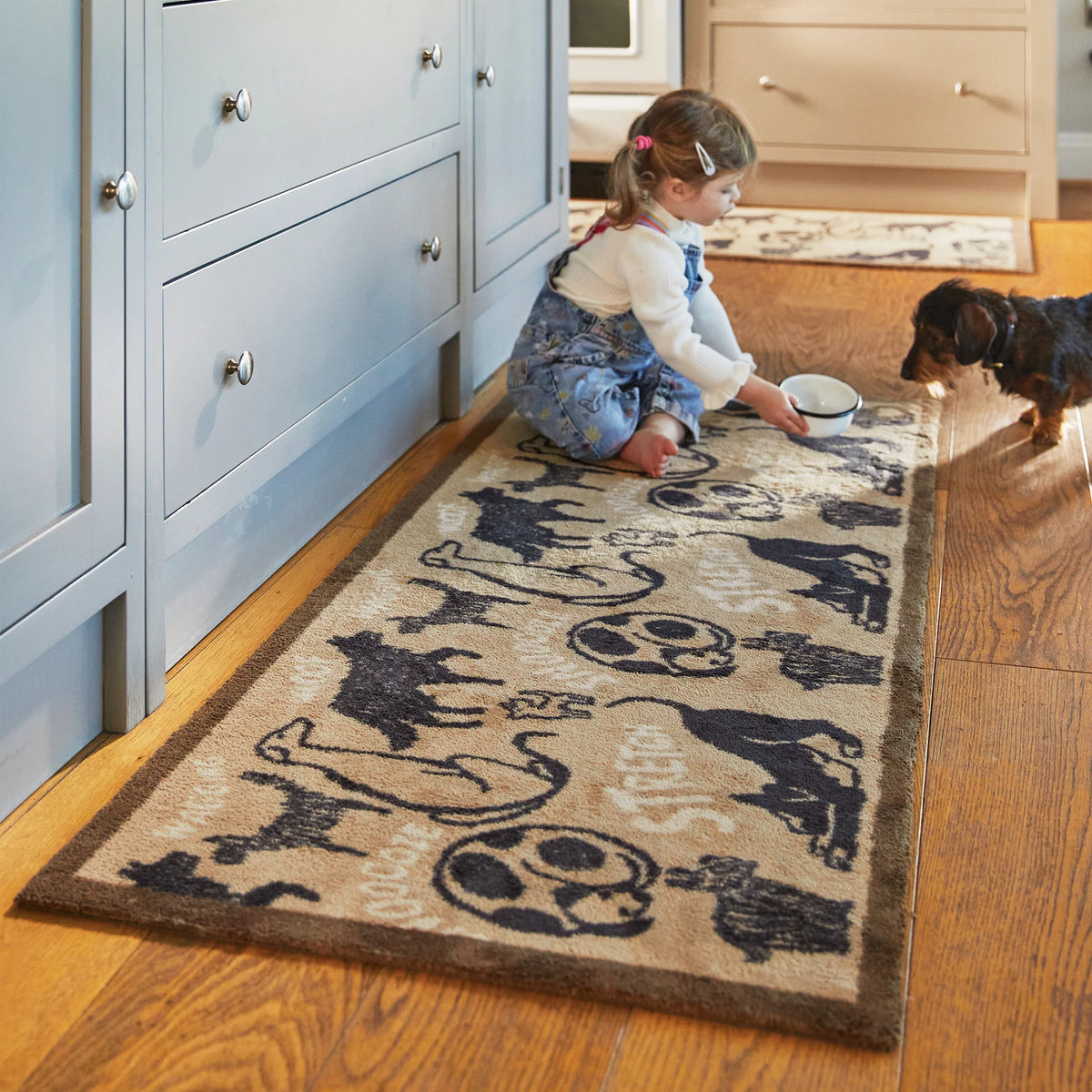 Child playing with a dog on a decorative rug in a home setting