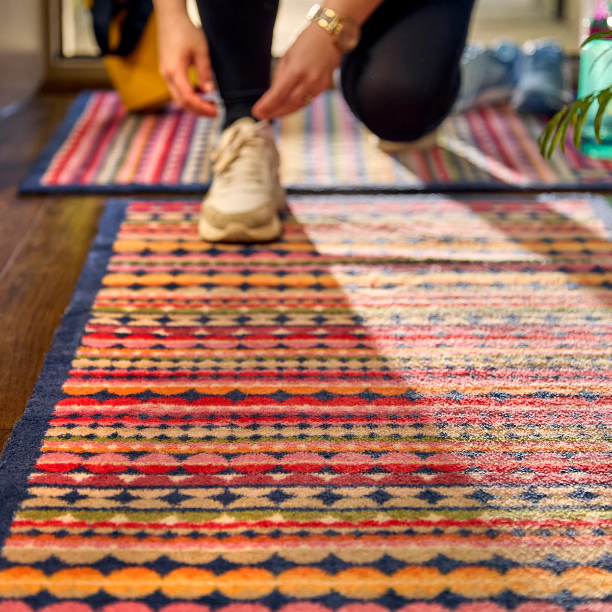 Person adjusting a shoe on a colorful patterned rug