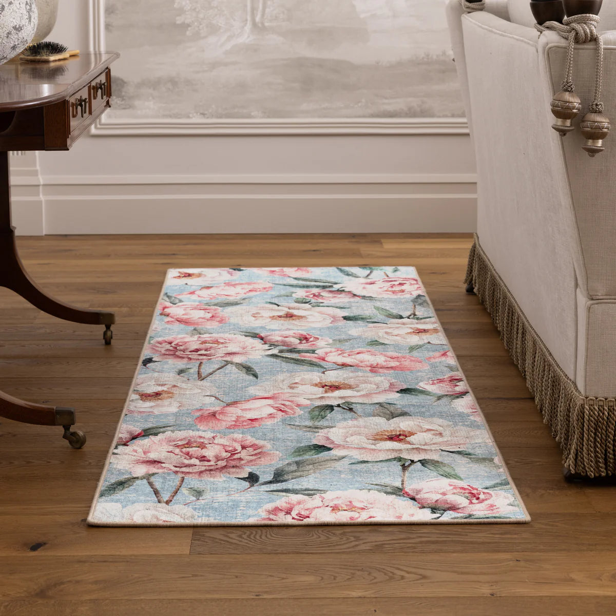 Floral patterned rug on a wooden floor with a sofa and side table in the background.