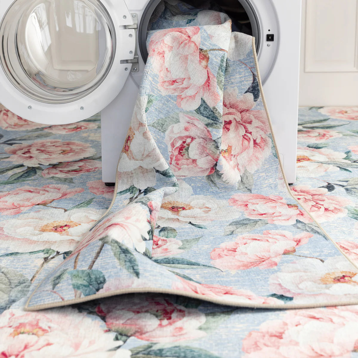Floral-patterned rug draped over a washing machine in a laundry room.