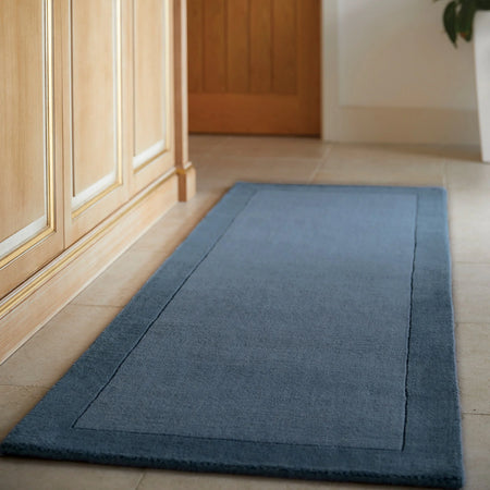 Blue rug on a wooden floor next to a glass door