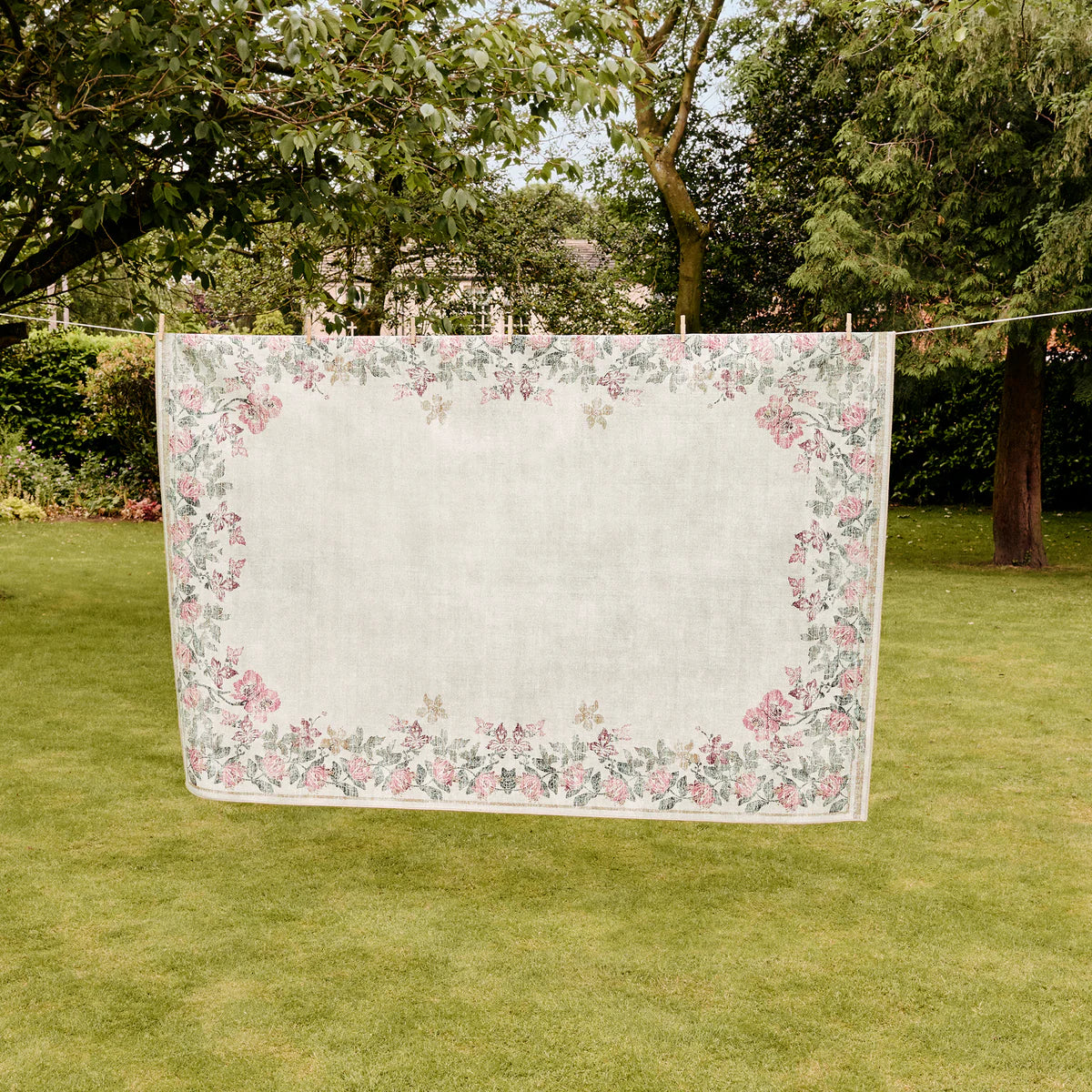 Floral-patterned blanket on a clothesline in a garden setting