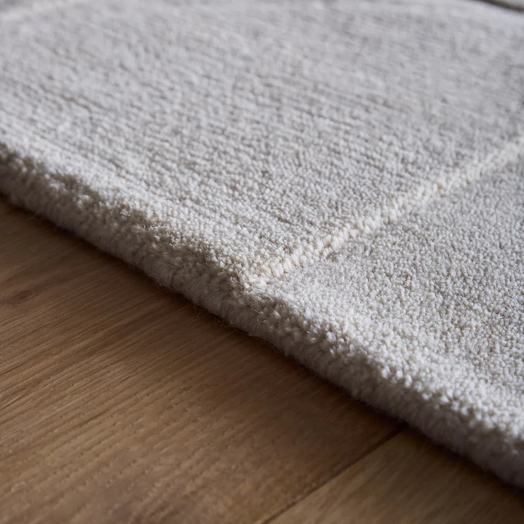 Close-up of a textured Penny Cream rug on a wooden floor