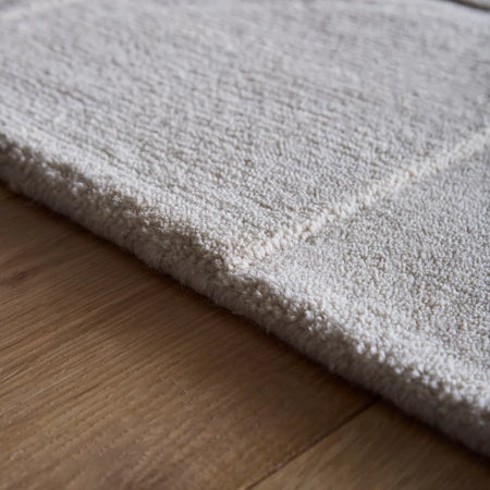 Close-up of a textured Penny Cream rug on a wooden floor