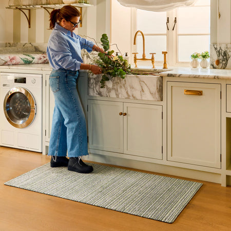Person cleaning a kitchen sink with plants in a home setting
