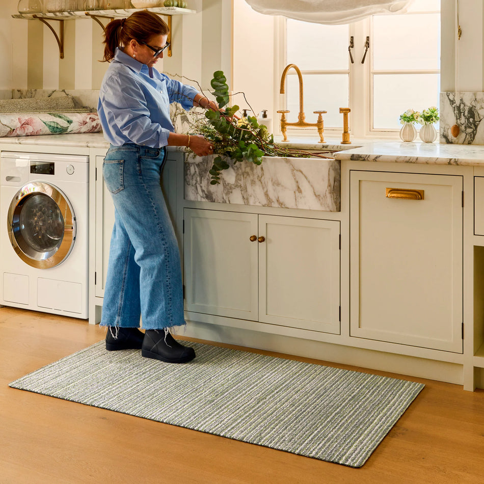 Person cleaning a kitchen sink with plants in a home setting