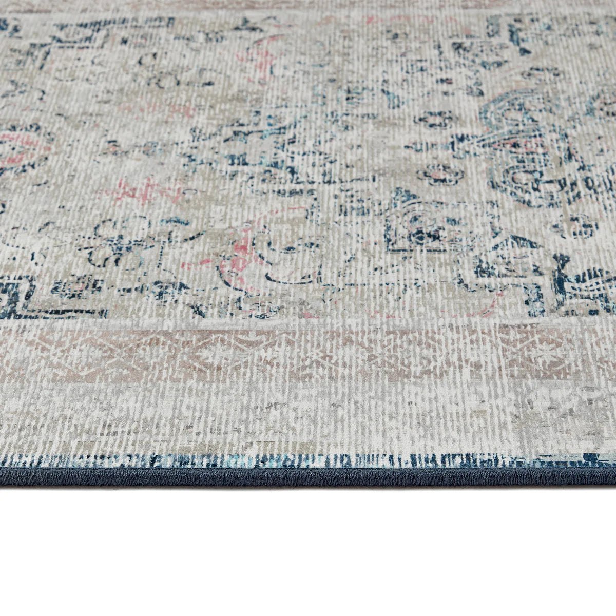 Close-up of a patterned rug with blue, pink, and gray colors.