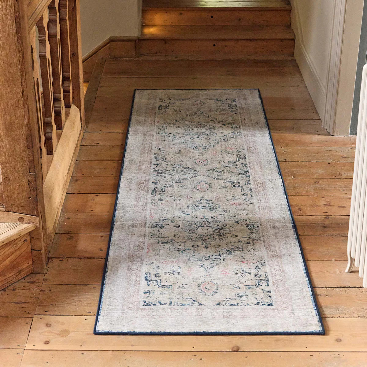 Long rectangular rug on a wooden floor with a staircase in the background
