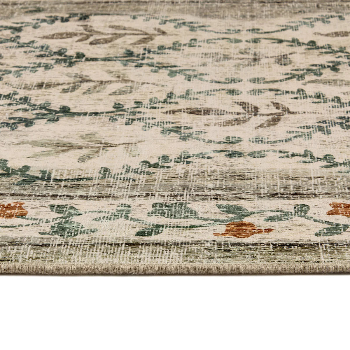 Close-up of a textured rug with floral patterns in beige, green, and brown.