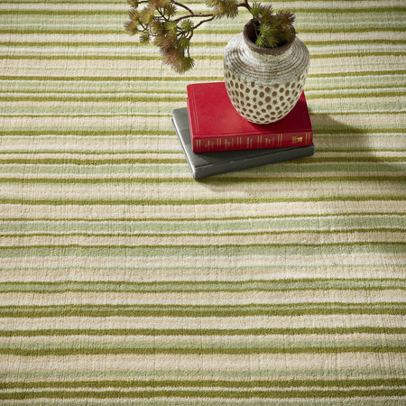origins Striped green and beige rug with a vase and books on top