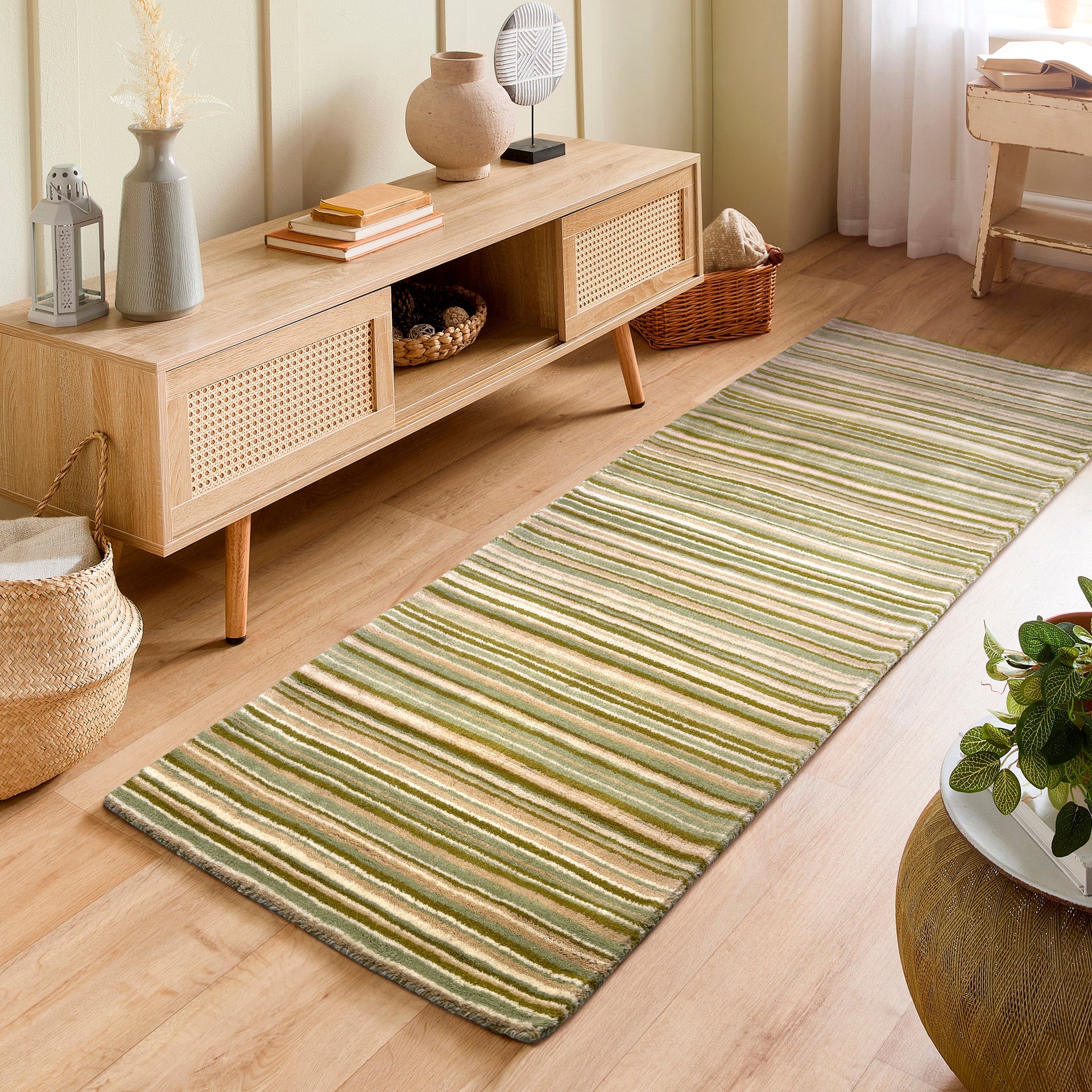 Living room with a wooden cabinet and a green striped rug on a light wood floor.