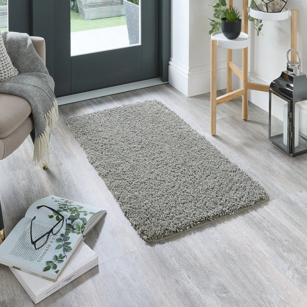 Grey rug on a wooden floor with books and glasses in a living room setting.