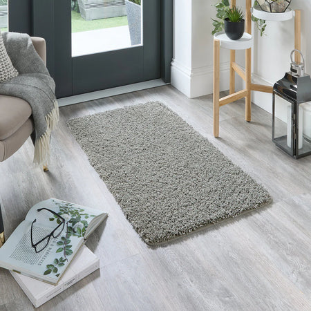 Grey rug on a wooden floor with books and glasses in a living room setting.