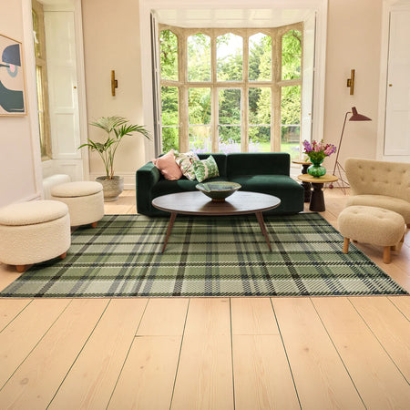 Living room with a green plaid rug, dark green sofa, and beige chairs.