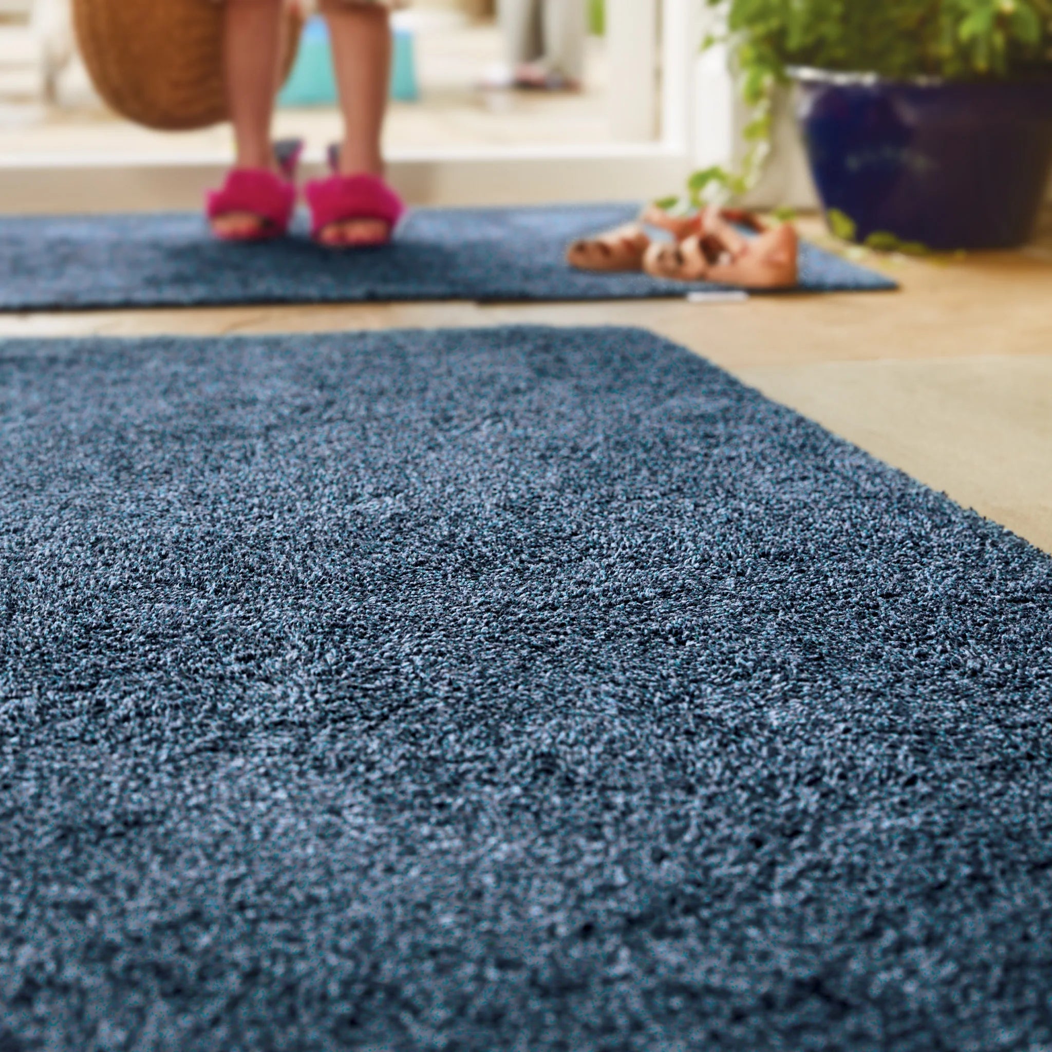 Blue rug with a person wearing pink slippers in the background