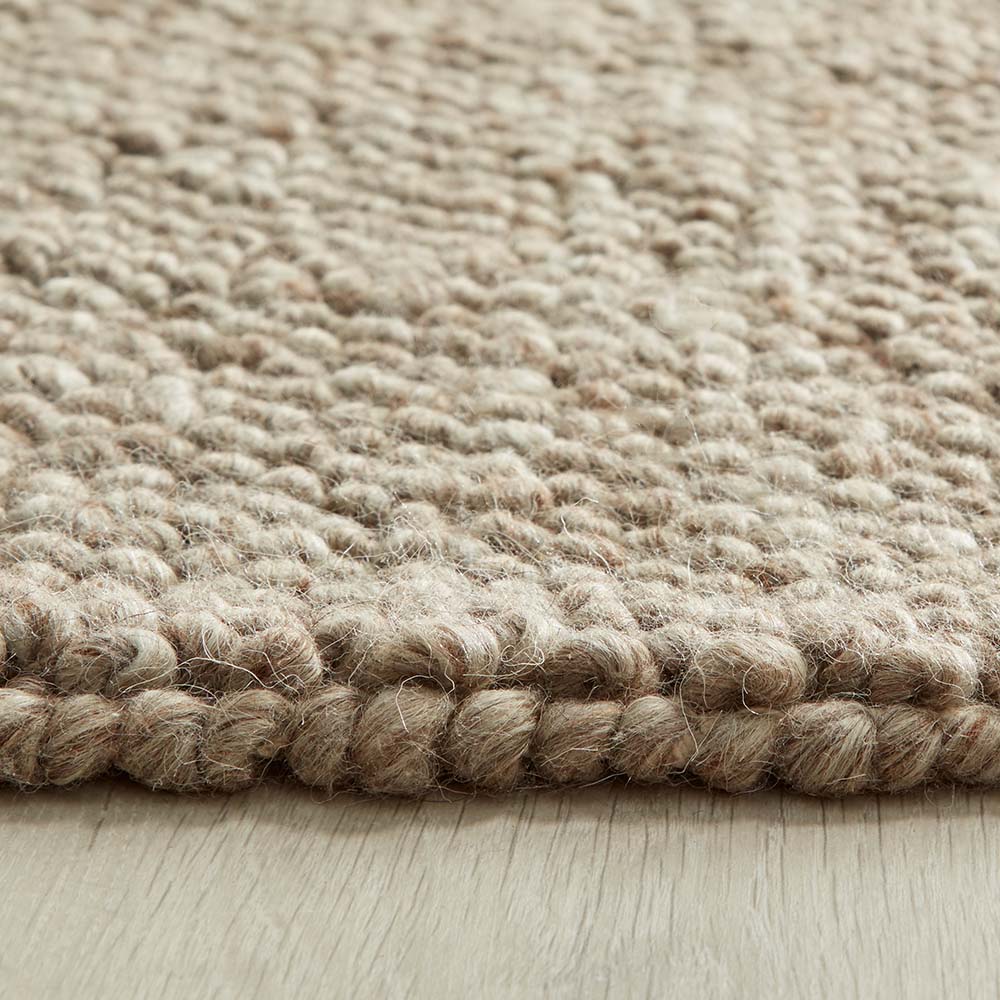 Close-up of a textured beige rustic rug on a wooden floor