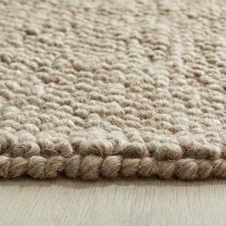 Close-up of a textured beige rustic rug on a wooden floor