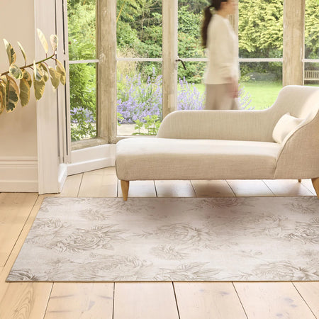 Living room with a beige sofa and a patterned rug on wooden flooring.