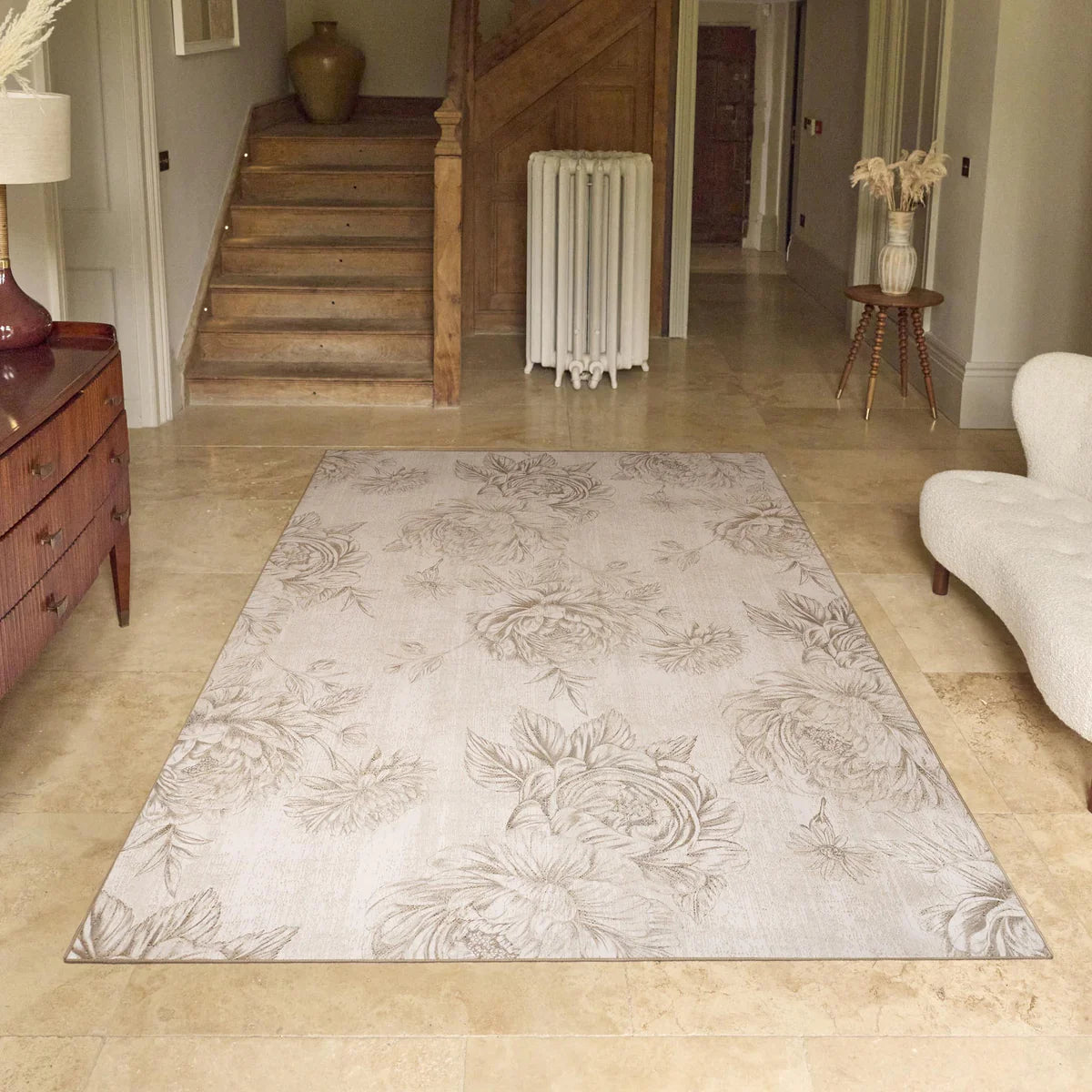 Floral patterned rug on a wooden floor with a staircase and furniture in the background