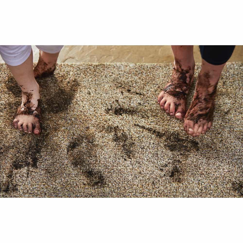 Two pairs of feet with mud on a carpet