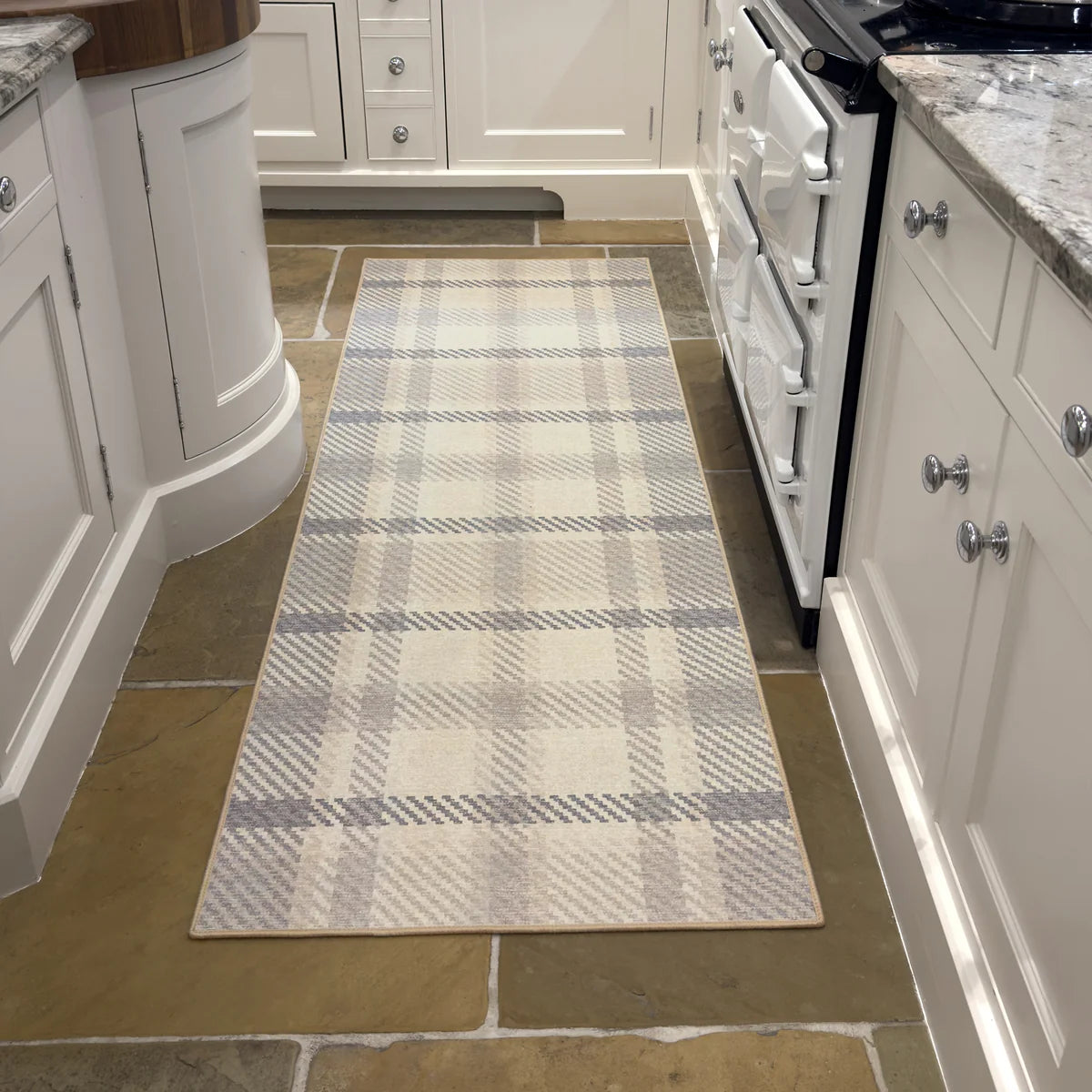 Plaid runner rug on a kitchen floor with white cabinets and appliances.