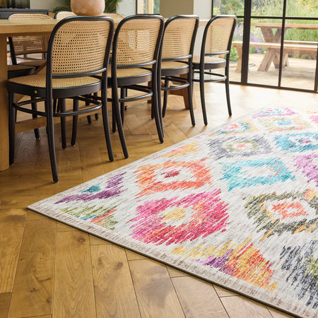 Colorful patterned rug on a wooden floor with chairs around a table.