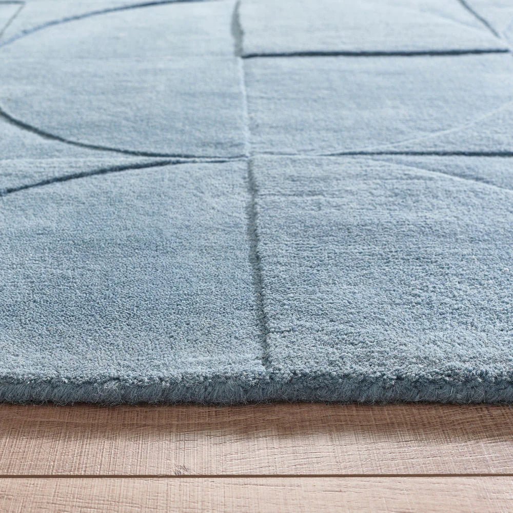 Close-up of a steel blue textured rug on a wooden floor