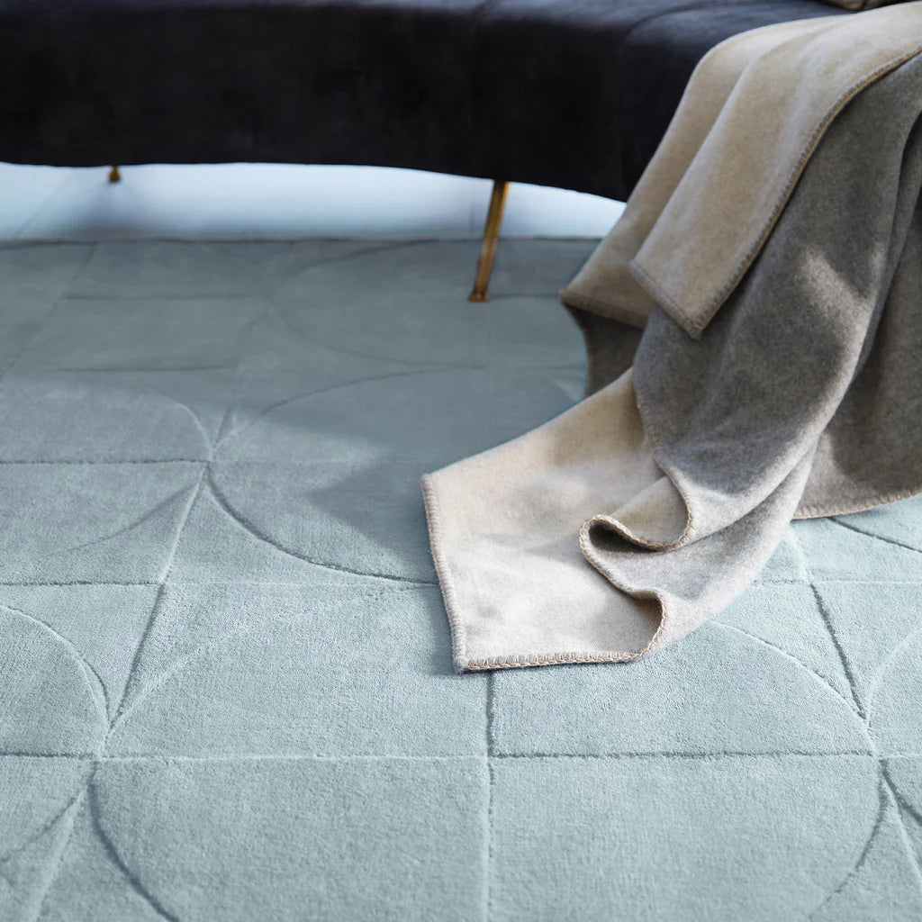 penny steel blue textured rug with a folded beige blanket on top