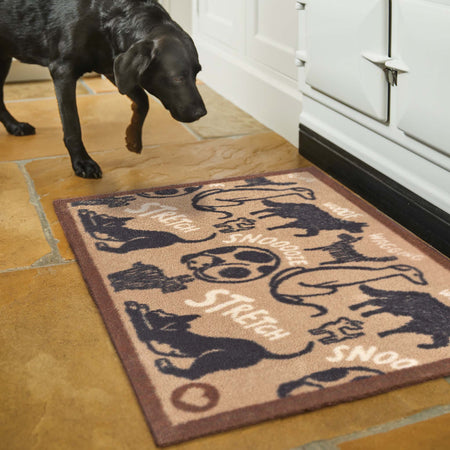 Dog standing on a doormat with dog-themed design in a kitchen setting