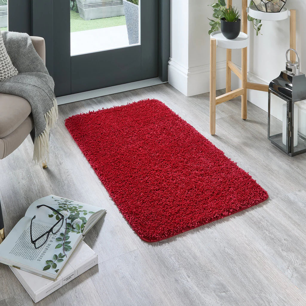 Red rug on a wooden floor with a book and glasses in the foreground