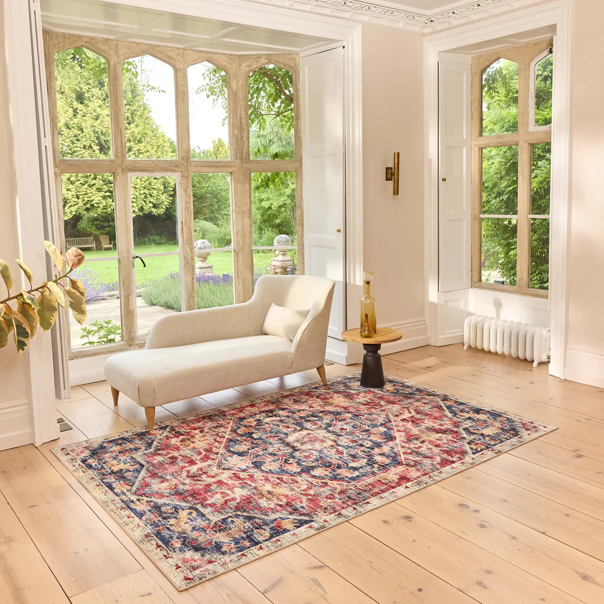 Living room with a floral rug, white sofa, and large windows.
