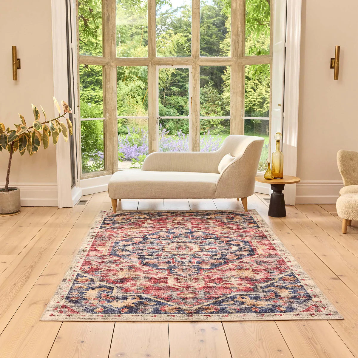 Living room with a patterned rug, sofa, and armchair near large windows.