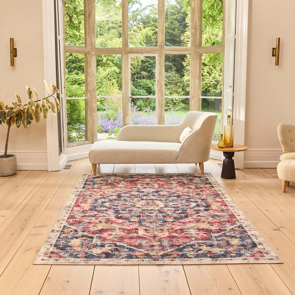 Living room with a patterned rug, sofa, and armchair near large windows.