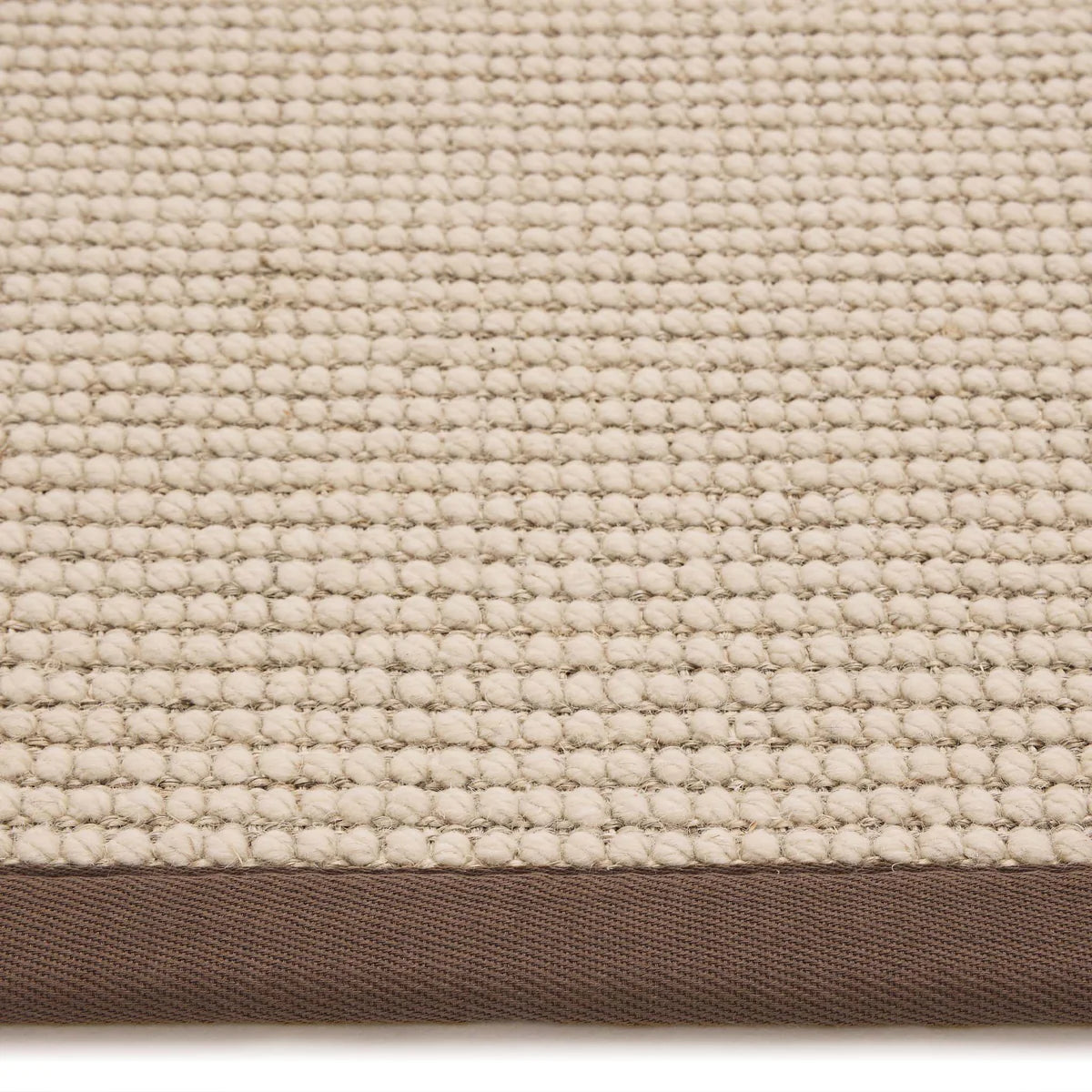 Close-up of a textured beige fabric with a brown border