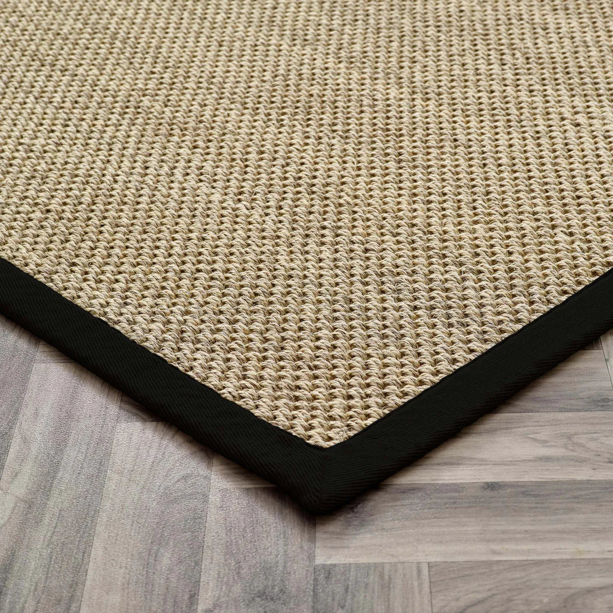 sisal Beige woven mat with a black border on a wooden floor