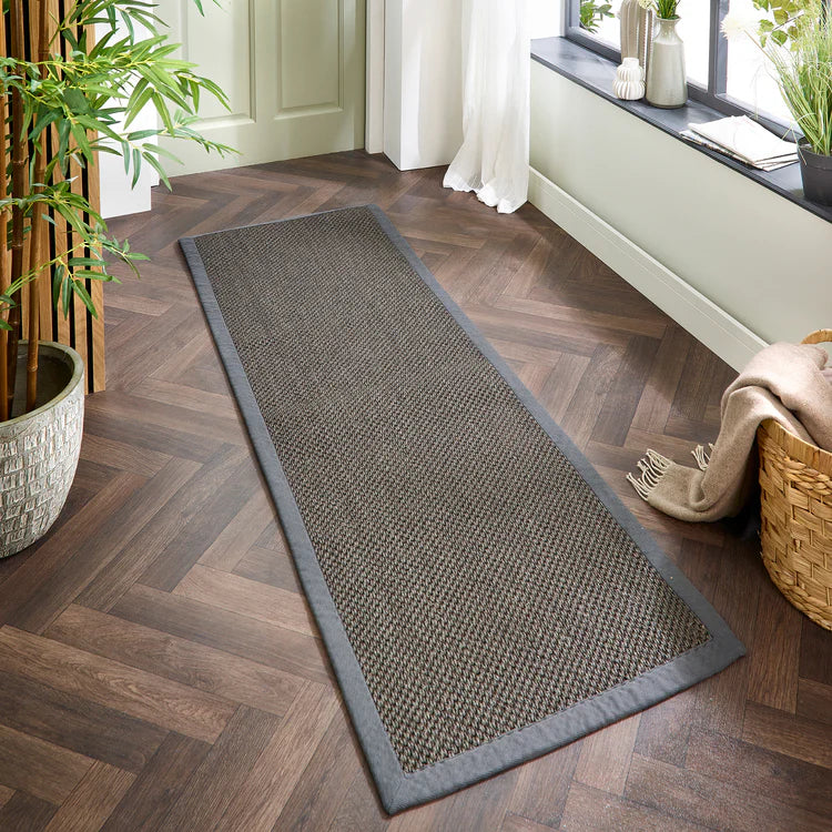 Long sisal dark grey with grey runner on a wooden floor with plants and a basket in the background
