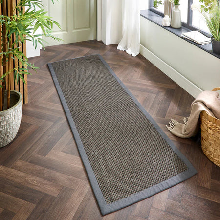 Long sisal dark grey with grey runner on a wooden floor with plants and a basket in the background