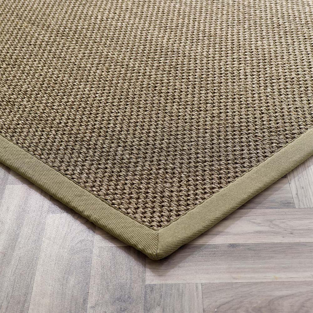 Close-up of a textured green with sage border rug on a wooden floor