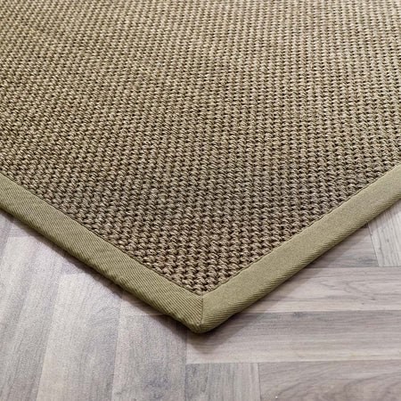 Close-up of a textured green with sage border rug on a wooden floor