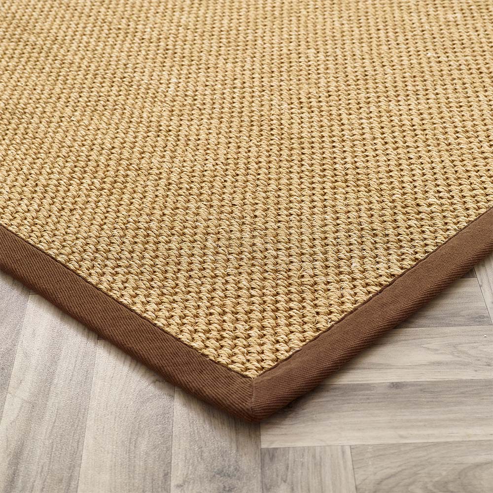 Beige woven rug with brown border on a wooden floor